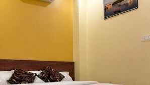 Een hotelkamer met een bed, airconditioning, een schilderij aan de muur en een houten hoofdbord.