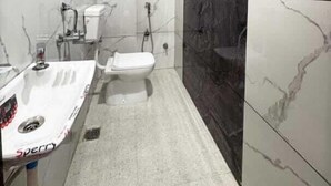 Een badkamer met een wit toilet, een witte wastafel en een douche.