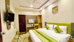 Een hotelkamer met een bed, een televisie, een bureau, een kledingkast en een schilderij aan de muur.
