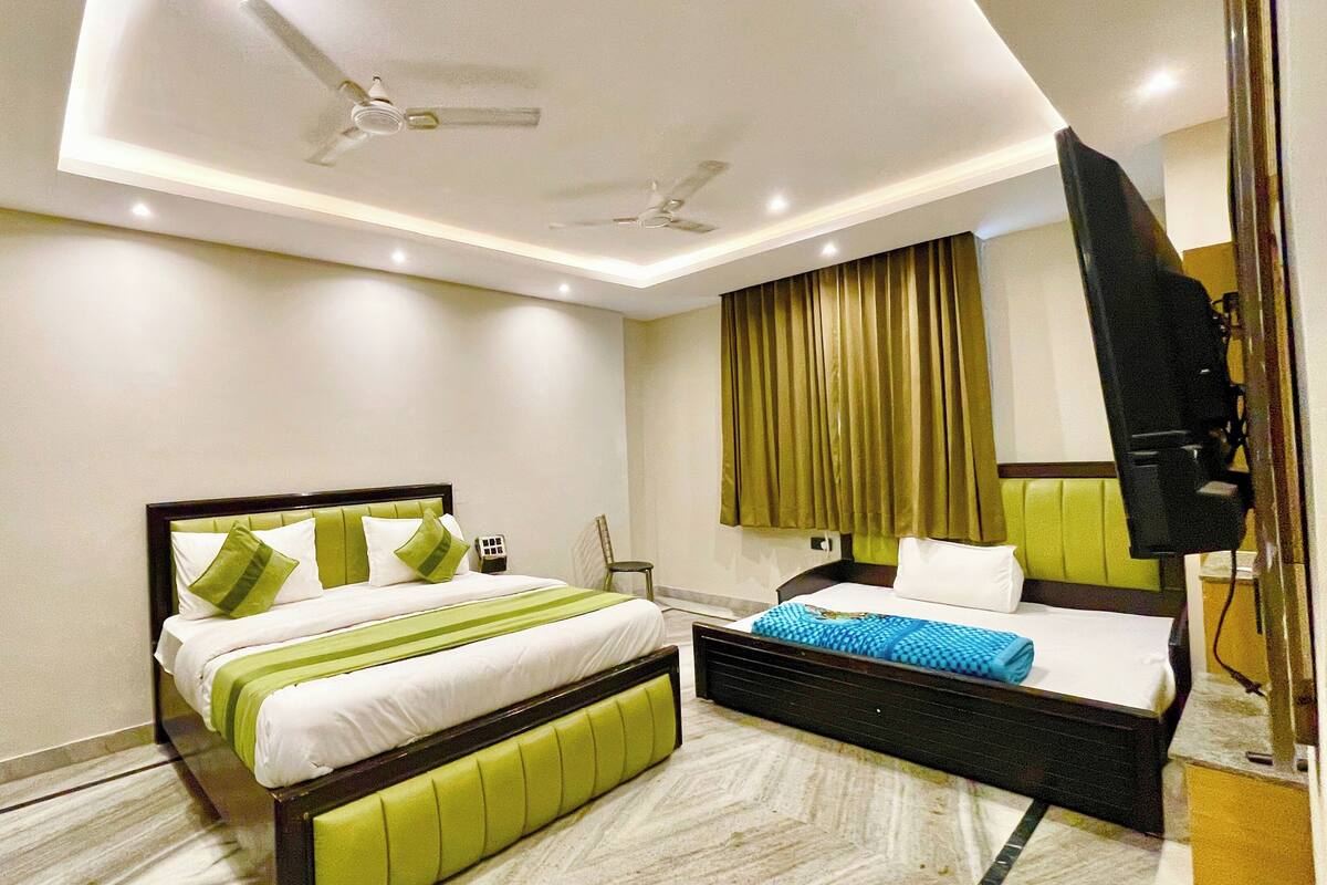 Une chambre d’hôtel équipée d’un lit, d’un bureau, d’une chaise, d’une télévision et d’un ventilateur de plafond.