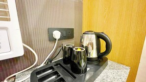 A kitchen area with a kettle, a coffee maker, and a power strip. - HOTEL PREMIUM K P  Near HAR KI PODDI   (Haridwar)