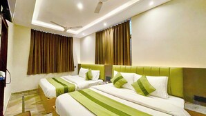 A hotel room with two beds, each with green and white bedding, and a ceiling fan. - HOTEL PREMIUM K P  Near HAR KI PODDI   (Haridwar)