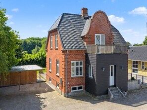 Et toetagers hus med skrå tag, murstensfacade og en lille tilbygning med mørk facade.