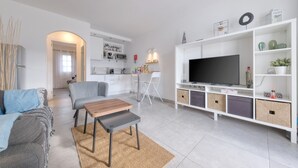 Ett modernt vardagsrum med en soffa, ett soffbord, en tv och ett köksområde i bakgrunden.