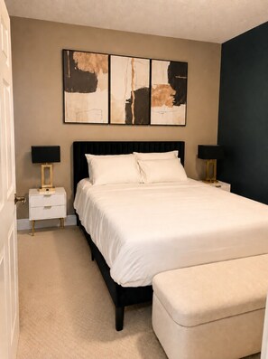 A bedroom with a bed, bedside tables, and a bench.