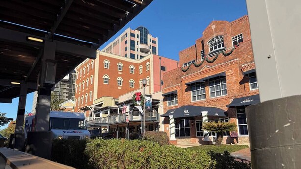 A commercial area with brick buildings, a FedEx truck, and a sign with a wreath. - Walk to FSU, Downtown & the Capitol-PRIME location (Tallahassee)