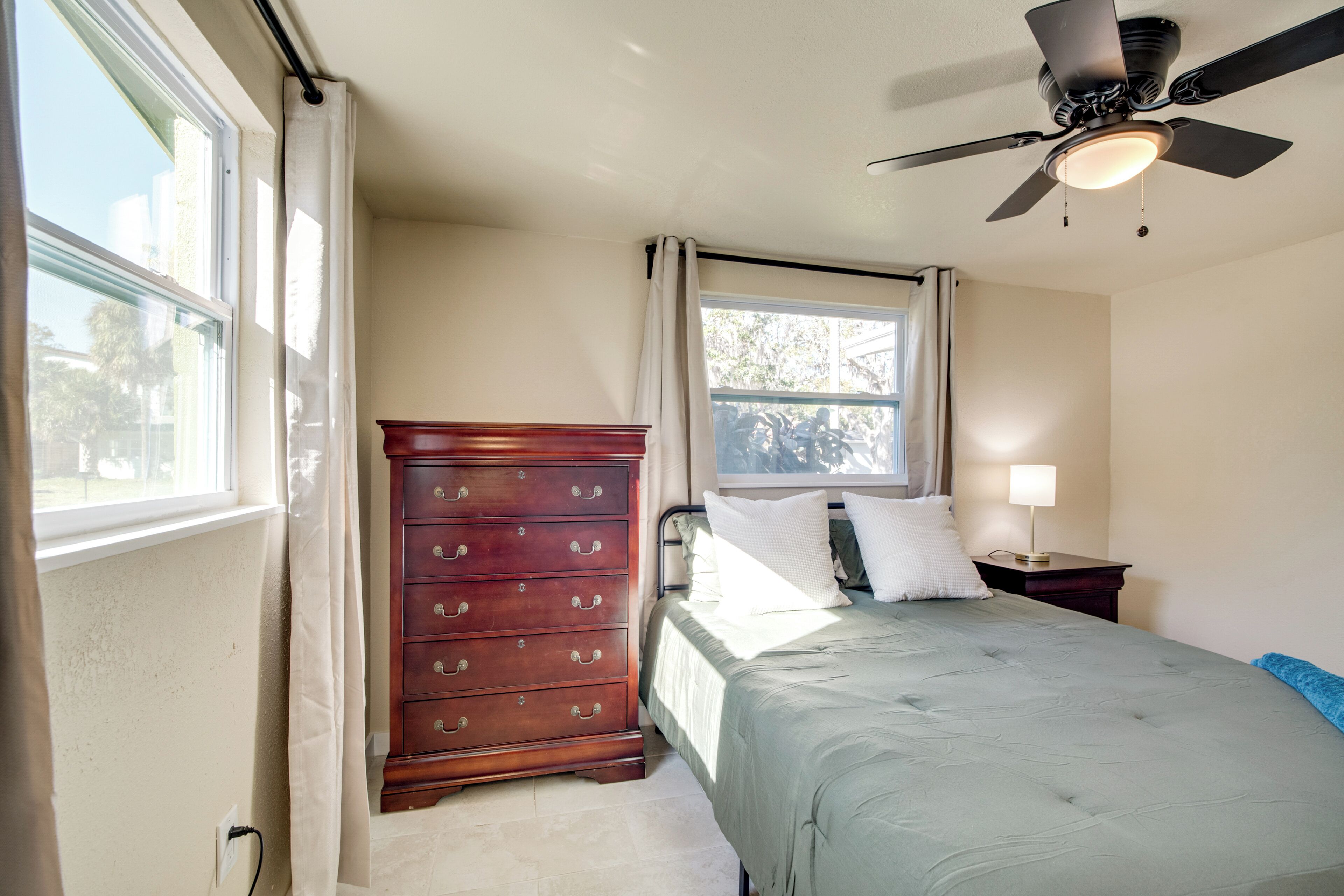 A bedroom with a bed, dresser, window, and ceiling fan.