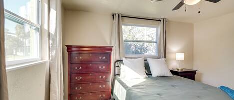 A bedroom with a bed, dresser, window, and ceiling fan.