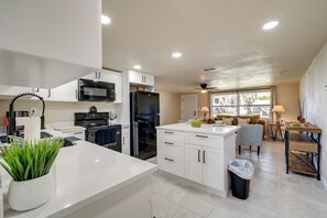 A modern kitchen with white cabinets, a black refrigerator, and a dining area with a table and chairs.