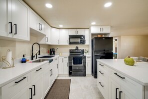 A modern kitchen with white cabinets, a black refrigerator, a microwave, and an oven.