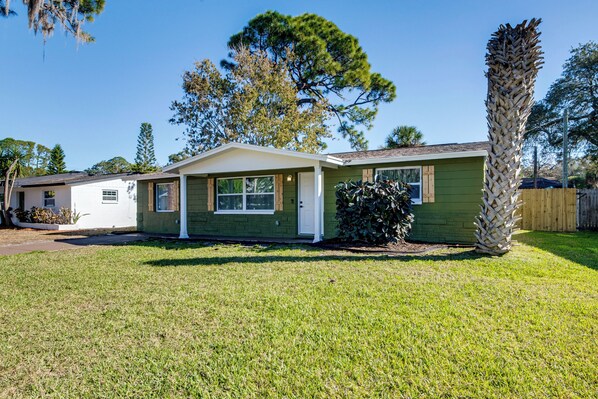 A single-story house with a green exterior, a front porch, and a well-maintained lawn.