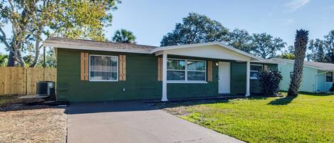 A single-story house with a green exterior, a front porch, and a small front yard.