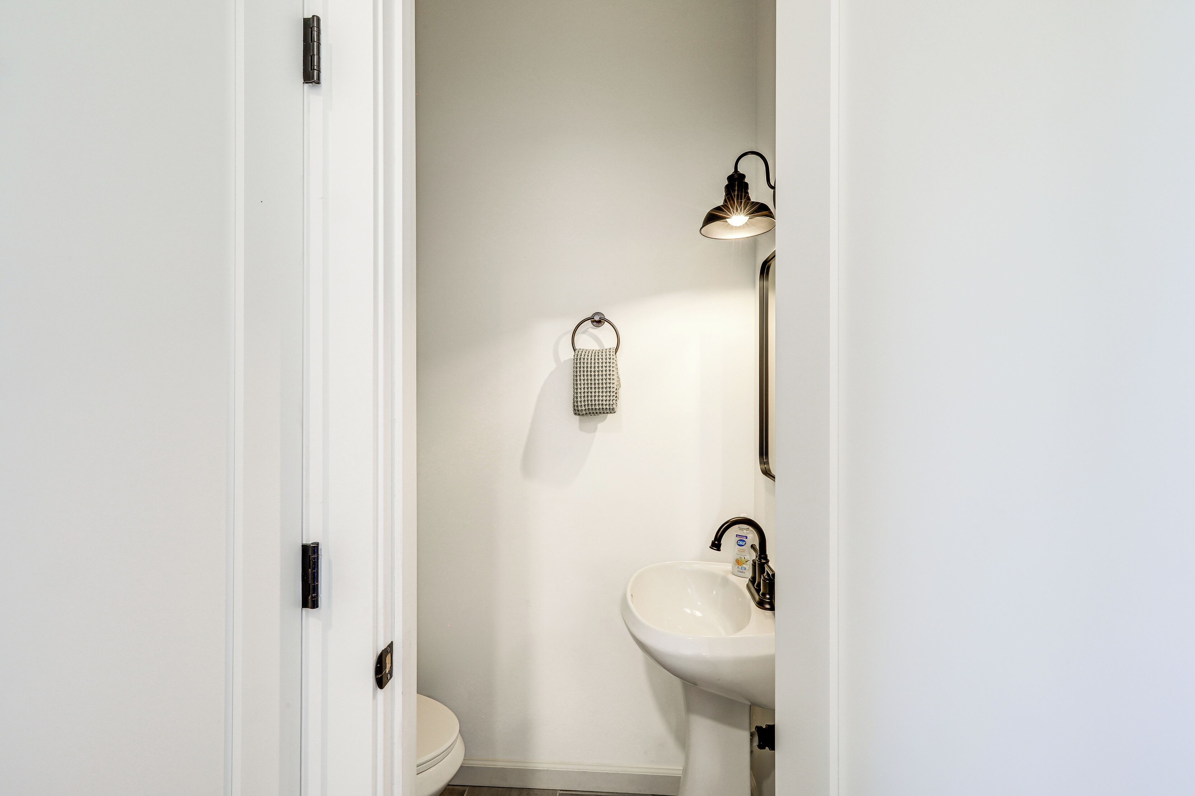 A bathroom with a toilet, a sink, and a towel hanging on the wall.