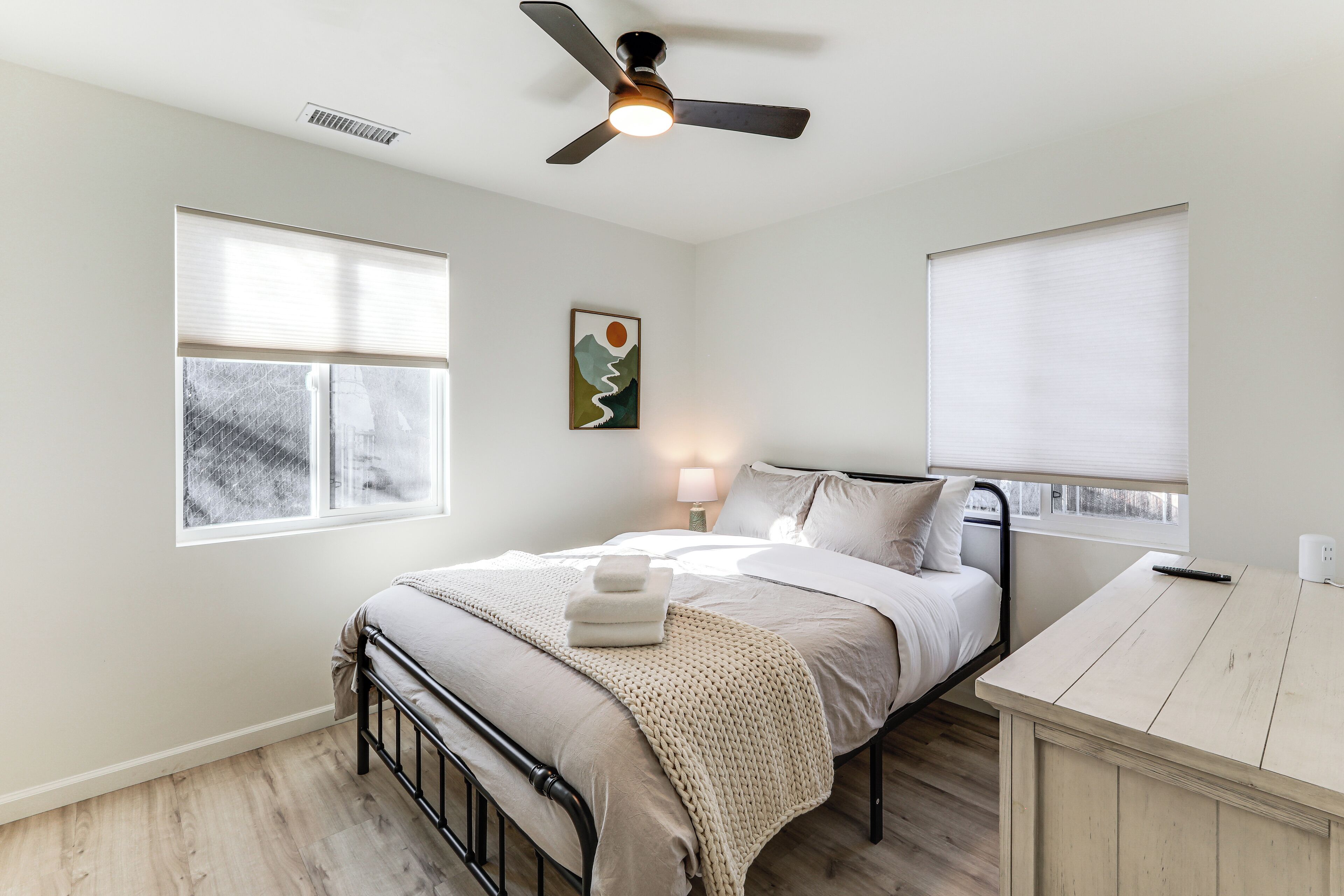 Une chambre à coucher avec un lit, une table de chevet, une lampe et un ventilateur de plafond.