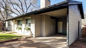 Une maison de plain-pied avec un garage, une cheminée et une véranda couverte.