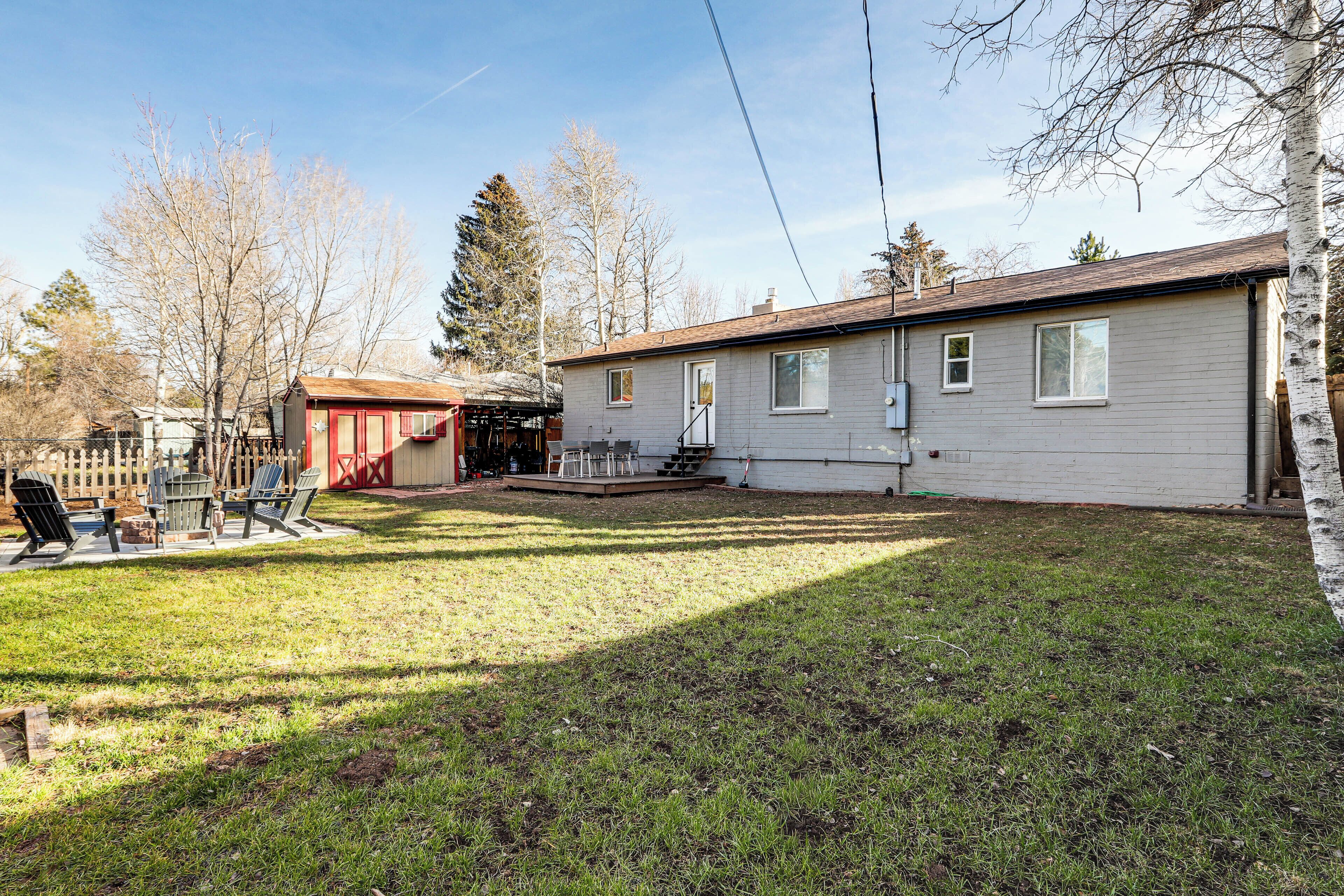 A single-story house with a covered patio area, a fenced yard, and a small shed.