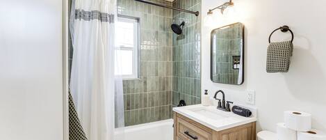 Un bagno con doccia, lavandino con specchio e toilette.