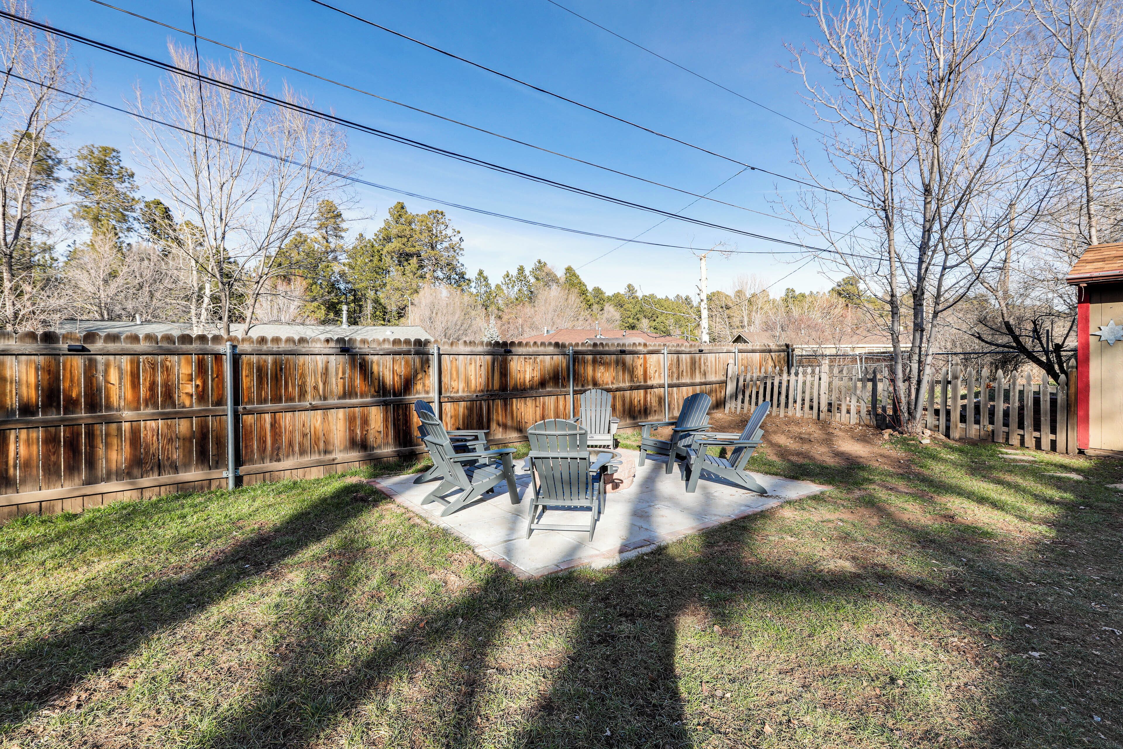 A patio with Adirondack chairs and a table, surrounded by a wooden fence.