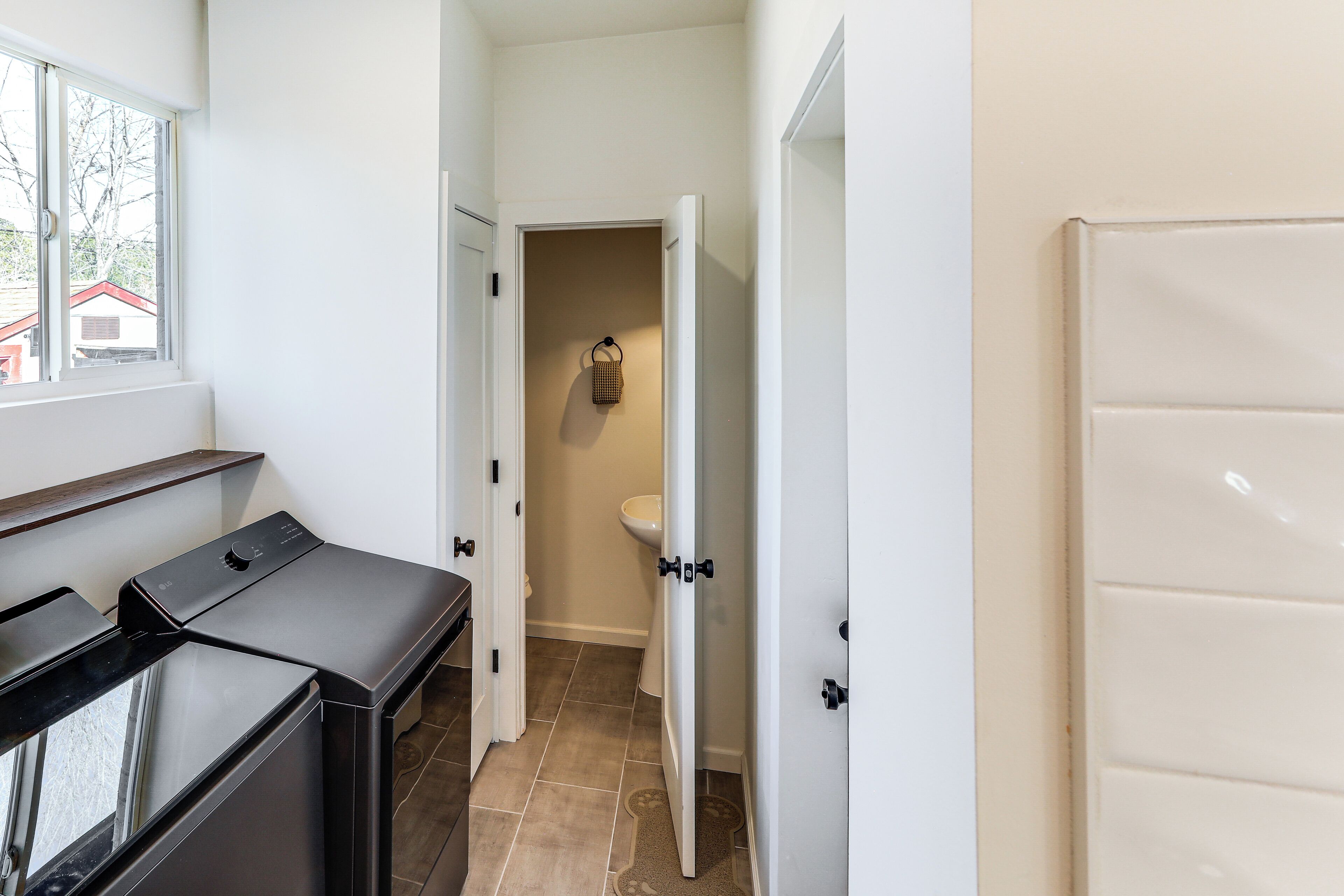 A laundry area with a washer and dryer, a window, and a view of the outside.
