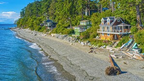 A beachfront property with multiple houses, a rocky shoreline, and a clear view of the ocean. - 2BR Oceanfront Cottage w/ Fire Table & Huge Deck (Point Roberts)