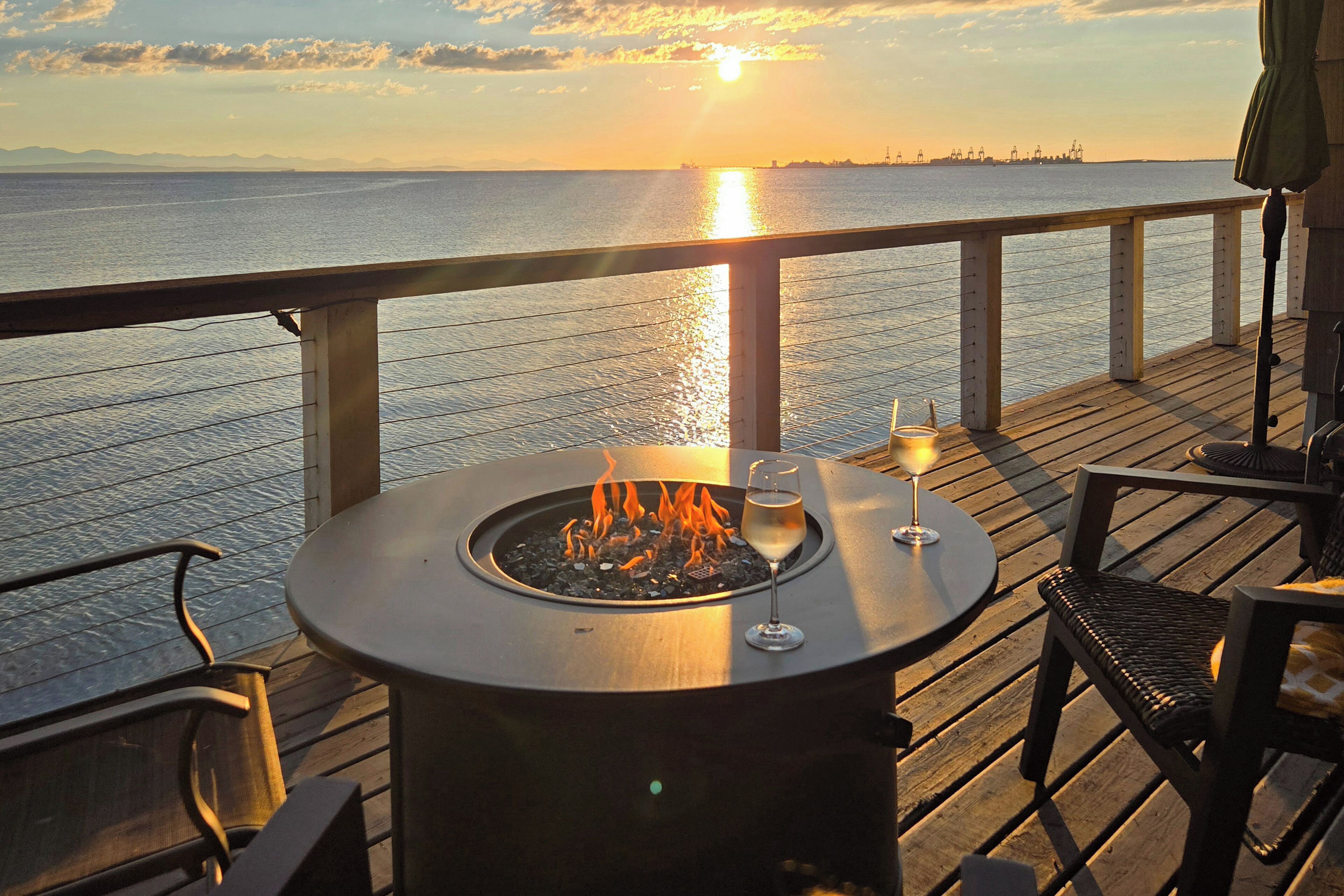 Una terraza con una mesa redonda, dos sillas, un brasero y una copa de vino.