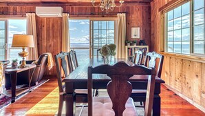 A wooden-paneled dining room with a large table, chairs, and a chandelier. - 2BR Oceanfront Cottage w/ Fire Table & Huge Deck (Point Roberts)