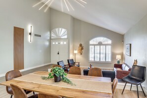 A dining area with a wooden table, chairs, and a potted plant. There are two sofas and a lamp in the background. - Stunning Renovated 5BR House W/pool 7 mil to Strip (Las Vegas)