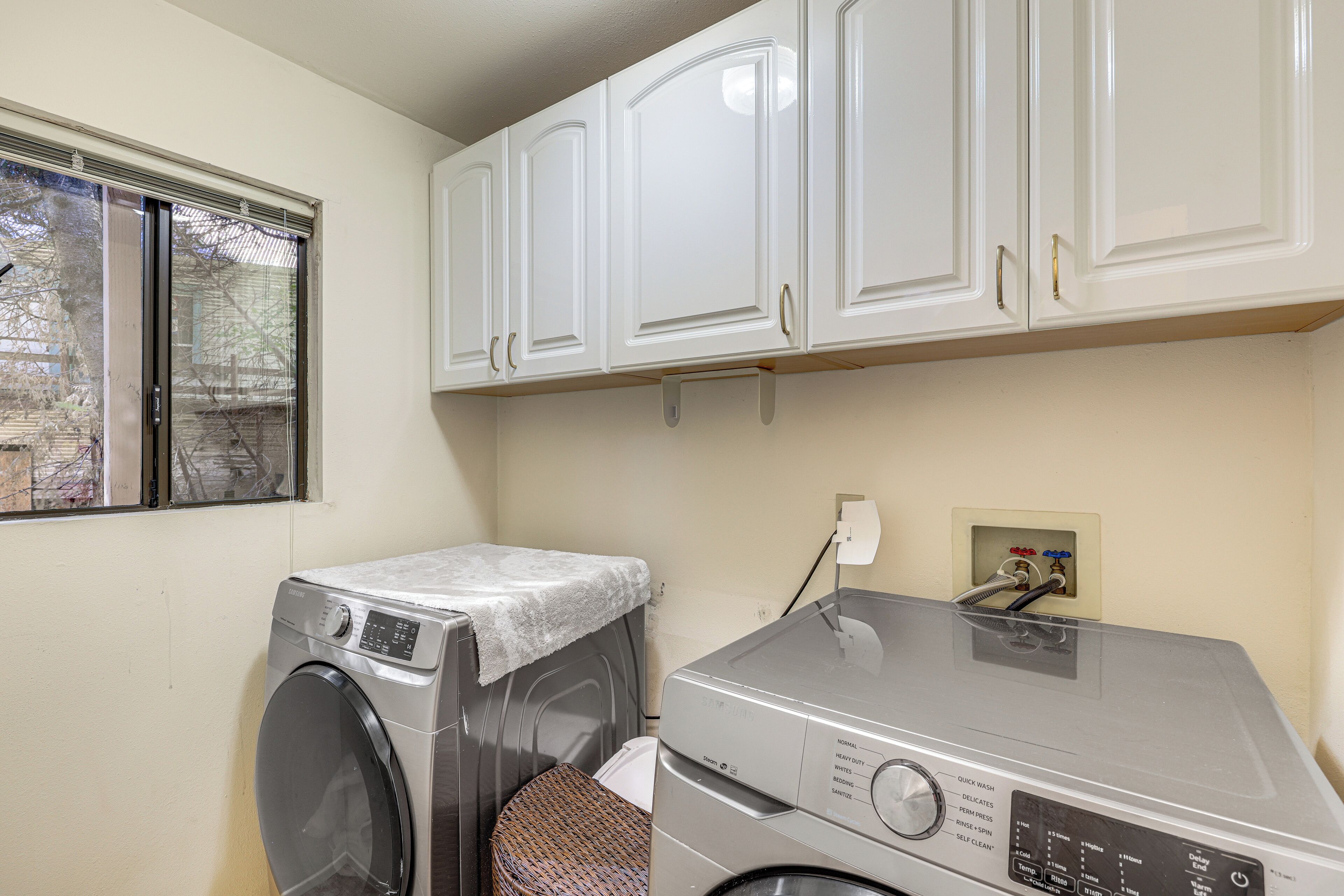 A laundry area with a front-loading washing machine and a stacked washer and dryer unit.