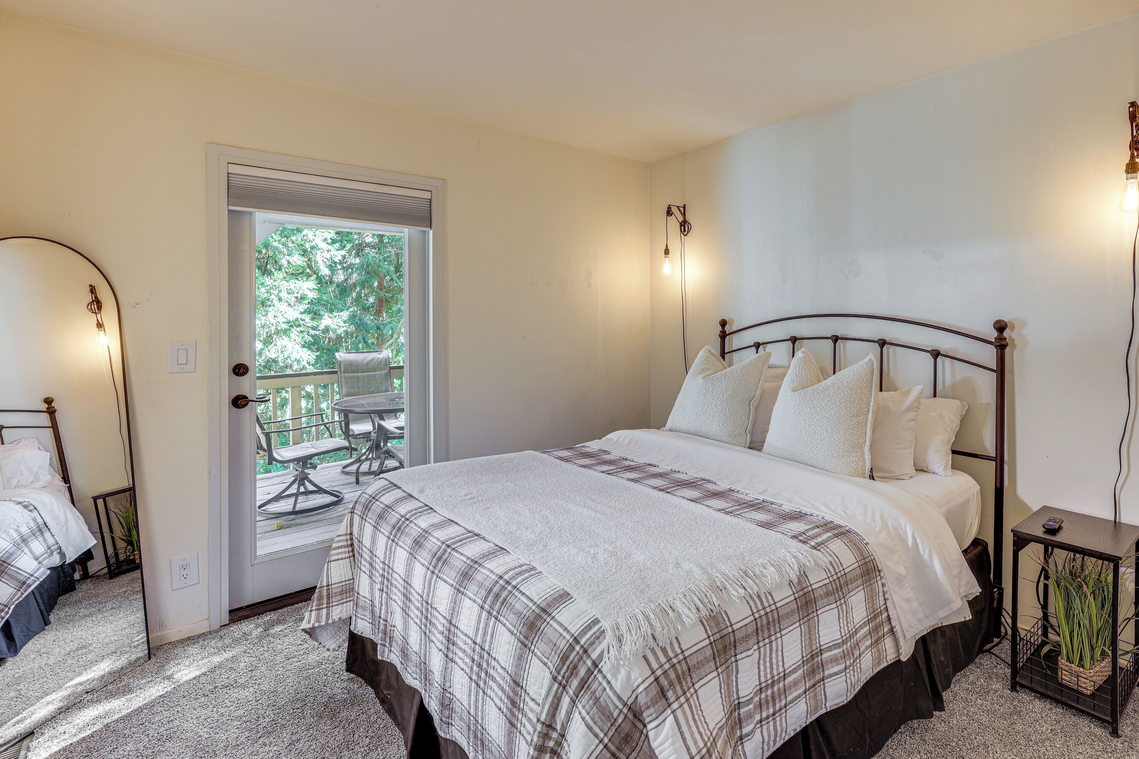 A bedroom with a large bed, a door leading to a balcony, and a small bedside table with a plant.