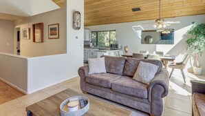 Un salon moderne avec un canapé marron, une table basse en bois et un coin repas comprenant une table et des chaises blanches.