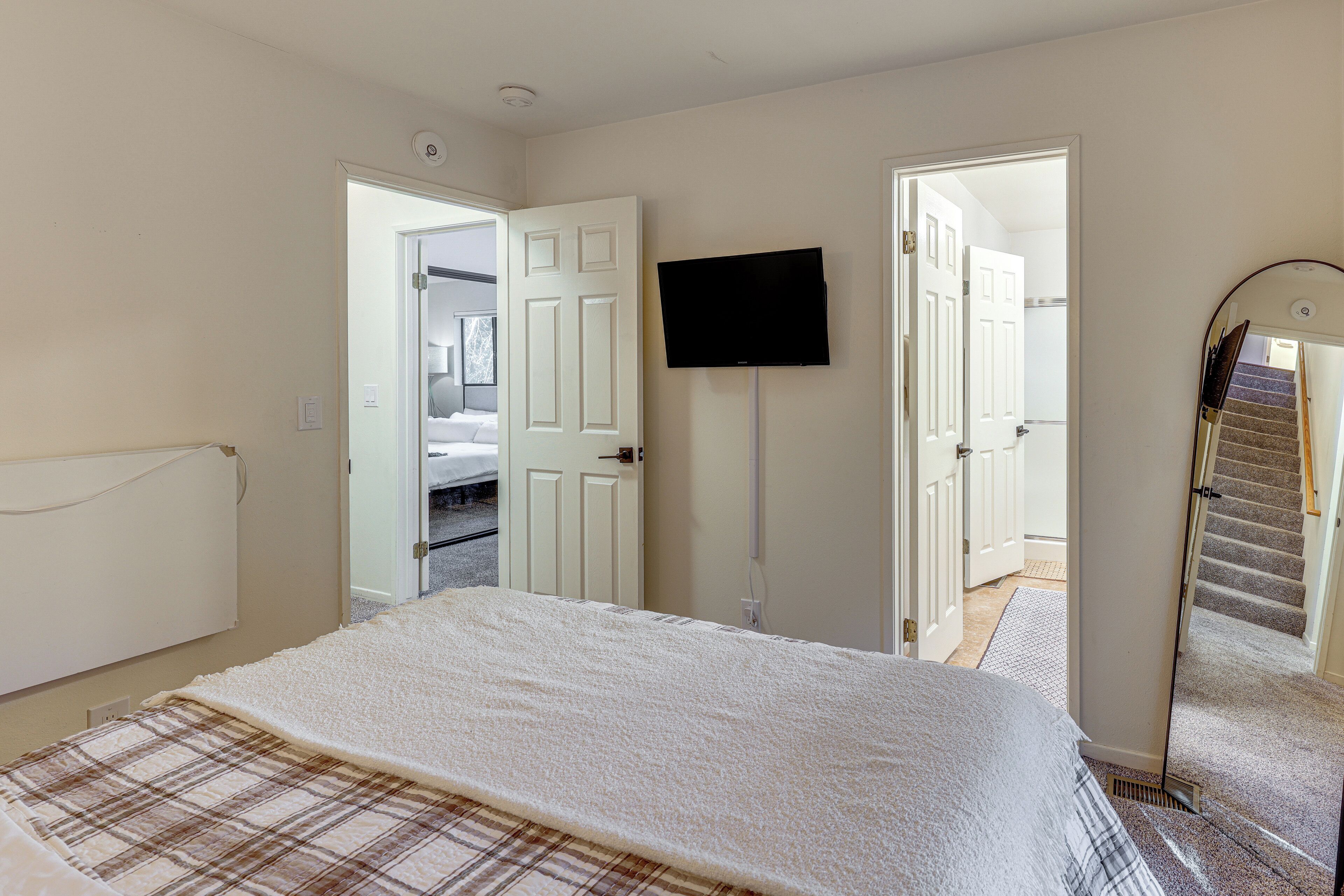 Ein Schlafzimmer mit einem Bett, einem Fernseher an der Wand und einer Treppe zu einem anderen Raum.