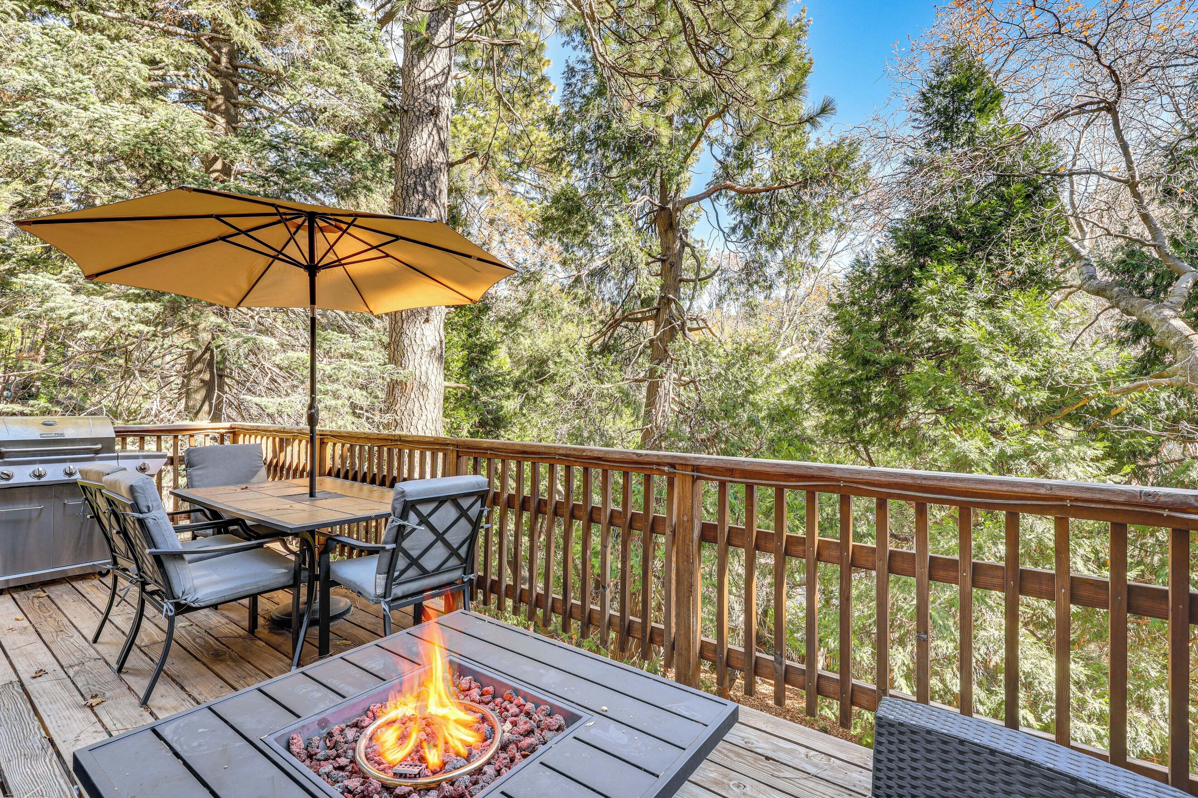 A deck with a grill, table, chairs, and a fire pit.
