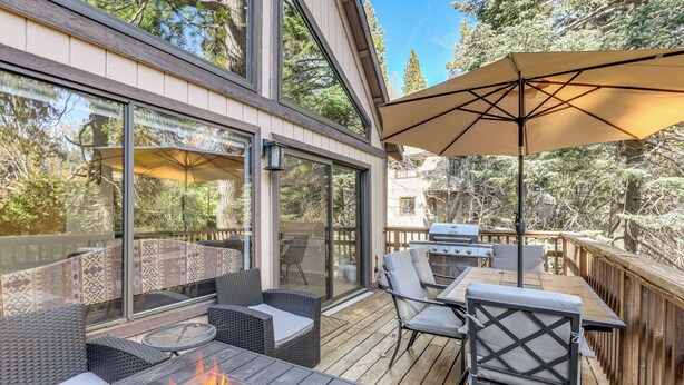 Une terrasse extérieure avec un foyer, des meubles en osier et un barbecue.