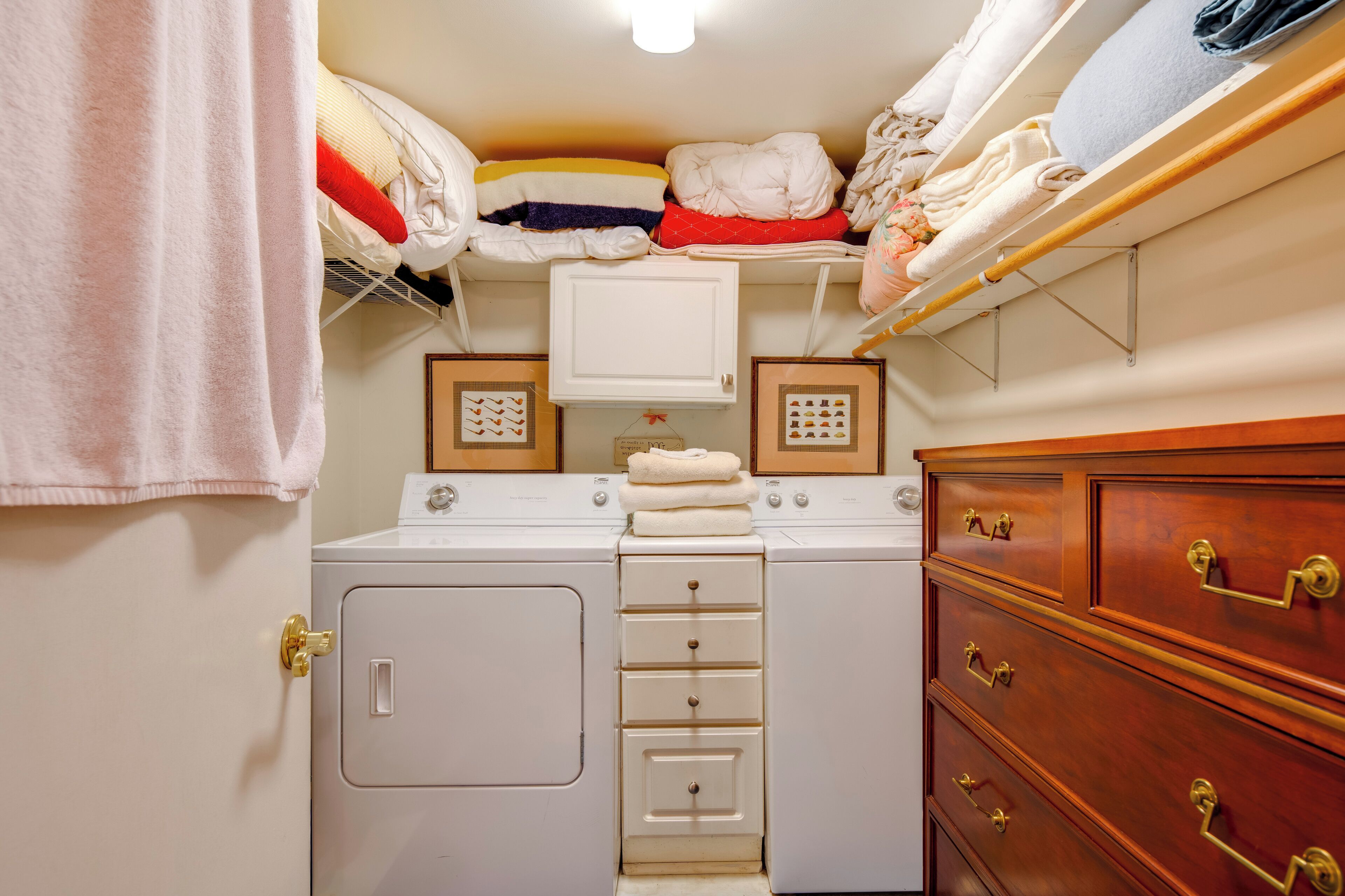 Une petite buanderie comprenant un lave-linge, un sèche-linge et des piles de serviettes.