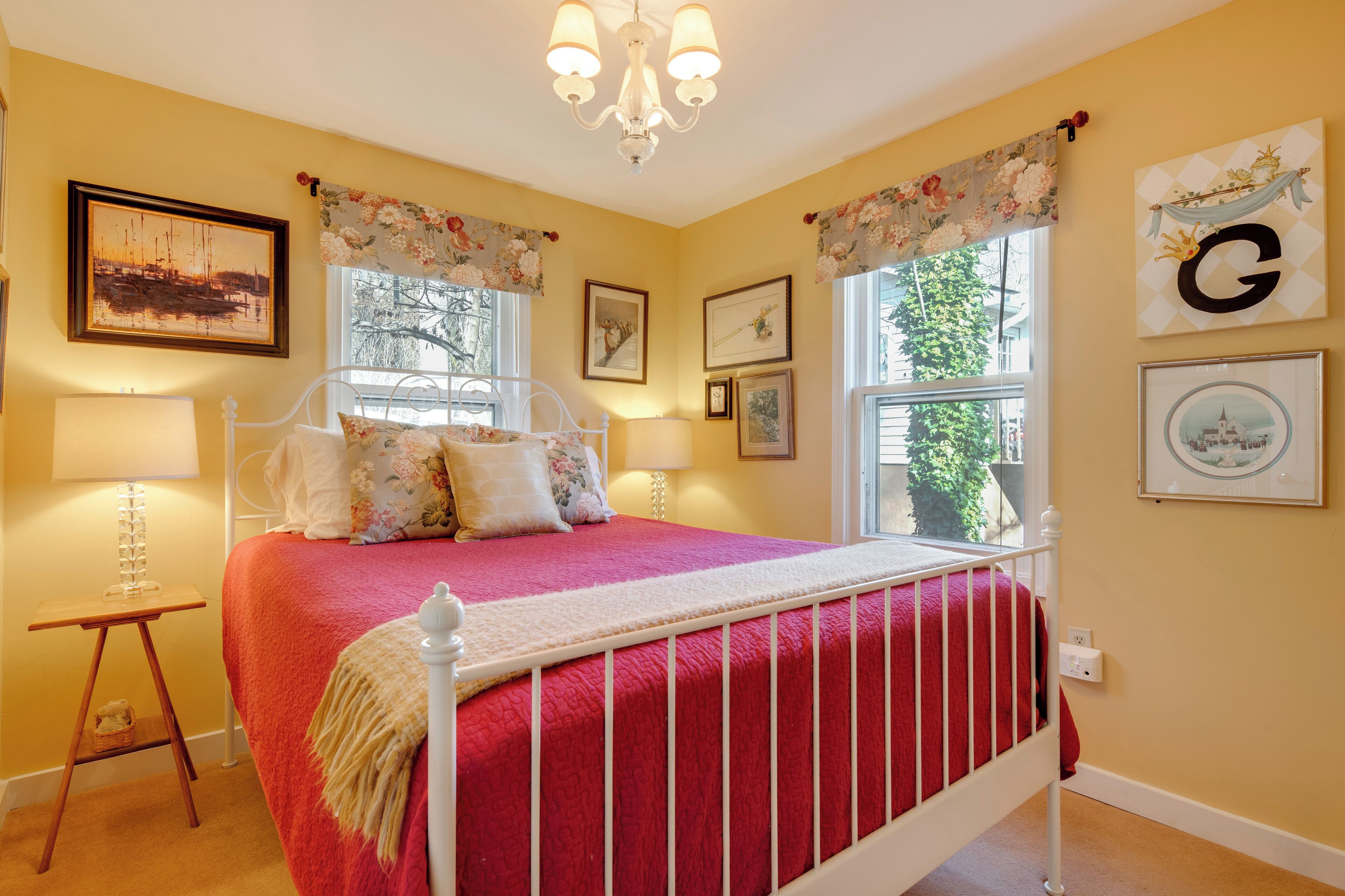 A bedroom with a bed, a nightstand, a lamp, and a chandelier.