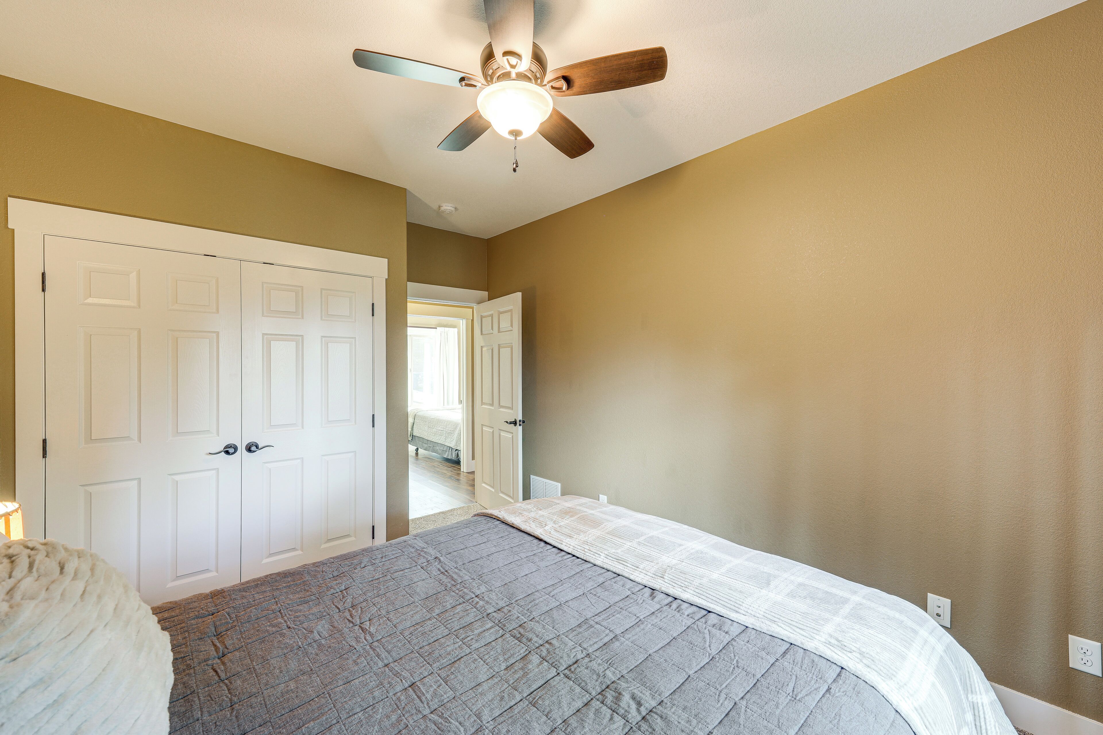 A bedroom with a bed, a ceiling fan, and a white door.
