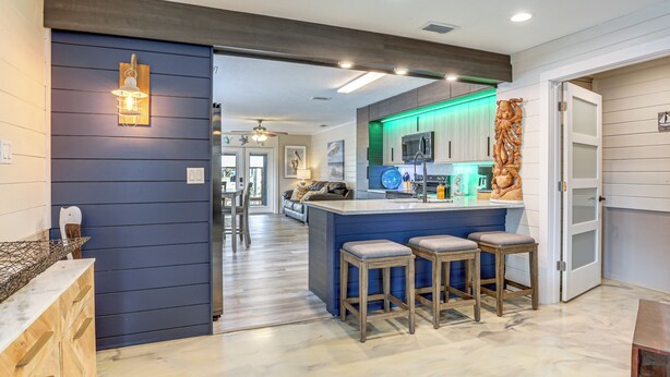 A modern kitchen with a bar area, wooden stools, and a decorative wall piece. - 'dunns Creek Lodge' - Private Boat Ramp! (Satsuma)