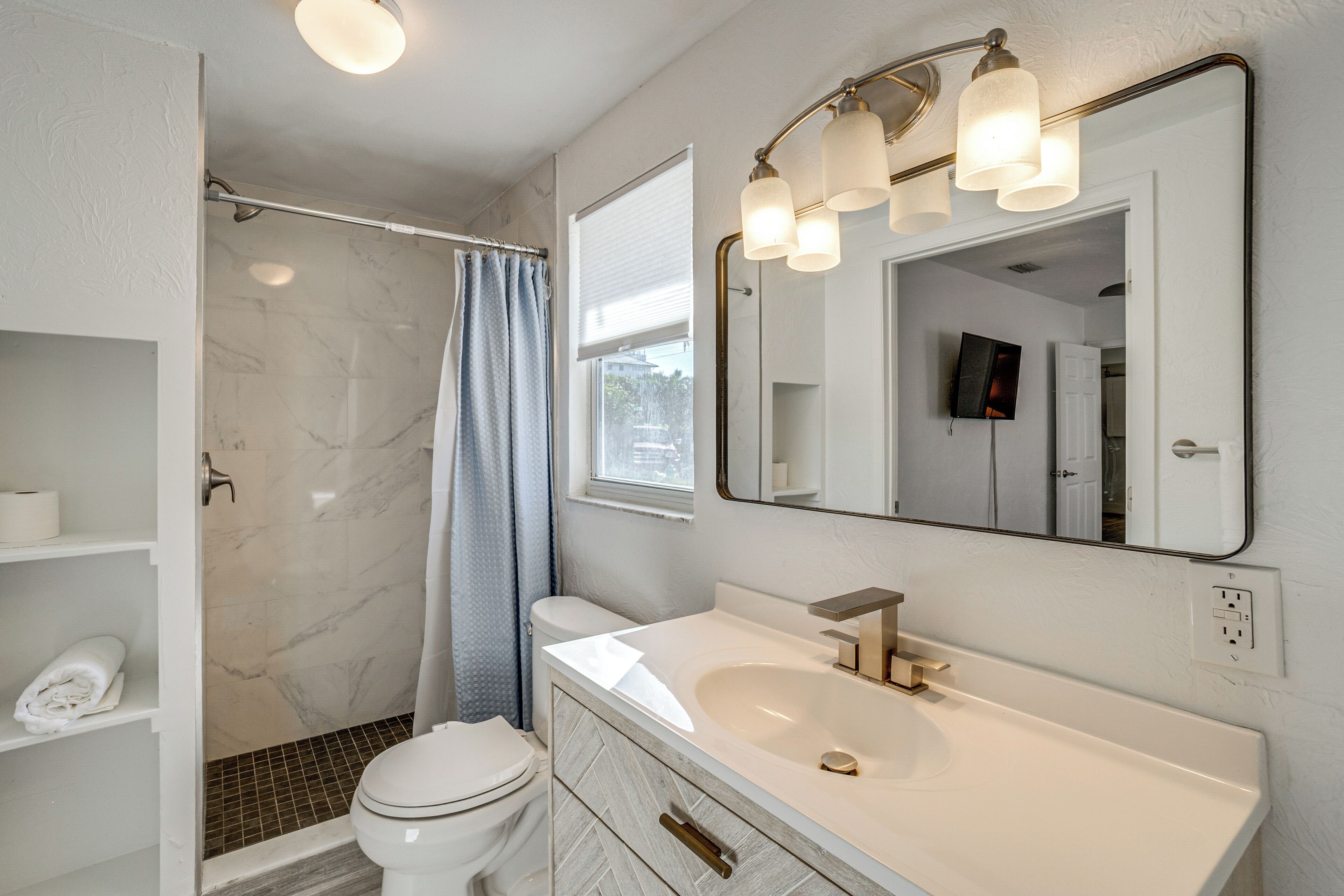 Un bagno moderno con un mobile lavabo bianco, uno specchio grande e una zona doccia.