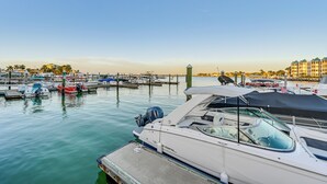 Un port de plaisance où sont amarrés différents types de bateaux, un ciel dégagé et, au loin, un bâtiment surmonté d’un toit végétalisé.