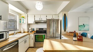 Une cuisine moderne équipée d’appareils électroménagers en acier inoxydable, d’un four encastré et d’un réfrigérateur. On y trouve également un coin repas avec une table et des chaises en bois.