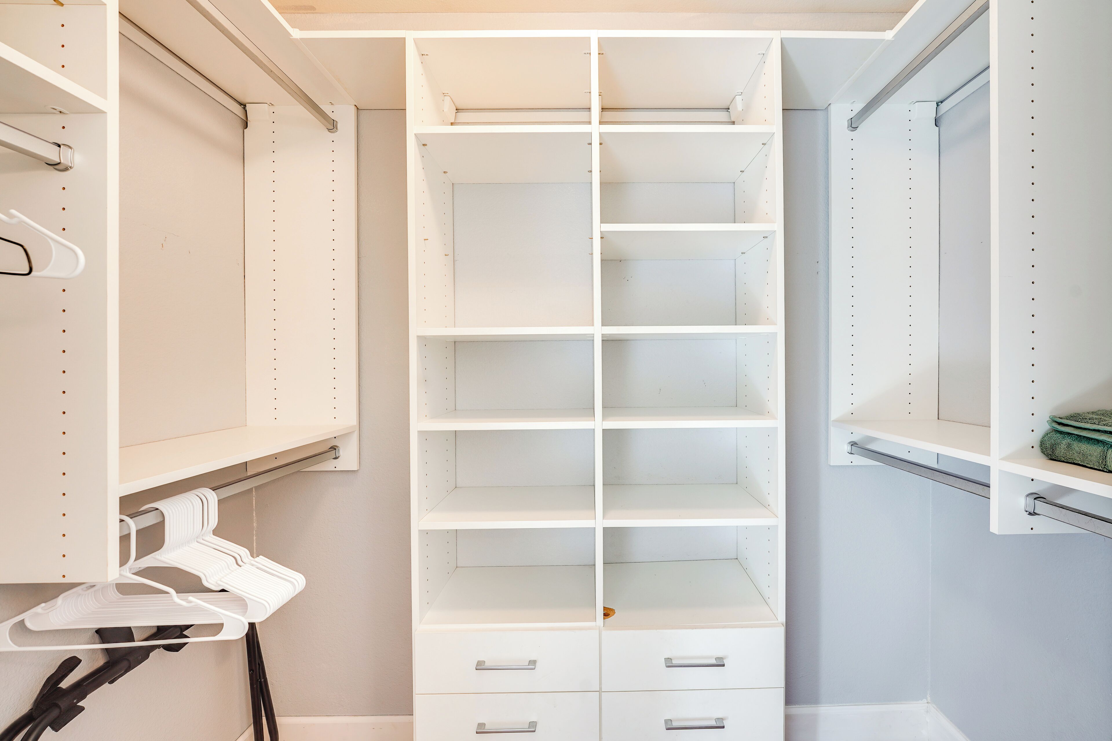 Un dressing avec des étagères ouvertes, des tiroirs et une tringle pour suspendre les vêtements.