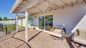 A covered patio with outdoor furniture, a brick floor, and a white exterior wall. - Pool + Putting Green: Quiet Scottsdale Oasis! (Scottsdale)