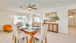 A dining area with a glass-top table, four upholstered chairs, a ceiling fan, and a wooden cabinet with a mirror. - Pool + Putting Green: Quiet Scottsdale Oasis! (Scottsdale)