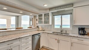 A modern kitchen with white cabinets, a dishwasher, and a view of the ocean. - Steps to Beach: Oceanfront w/ Panoramic Gulf Views (Destin)