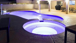 A hot tub with a circular design, surrounded by a patio area with outdoor furniture and a covered seating area. - Private Pool, Spa! Updated Home Near London Bridge (Lake Havasu City)