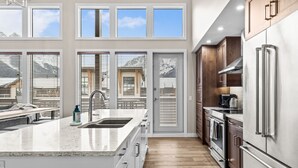 Una cocina moderna con una isla grande, electrodomésticos de acero inoxidable y vistas a un paisaje montañoso a través de las ventanas.