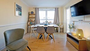 A modern living room with a dining area, a flat-screen TV, and a bookshelf. - Little Venice in Paddington central London 3 bedroom apartment (London)