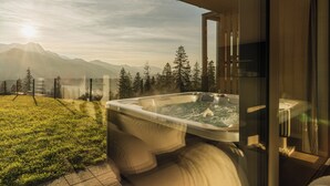 Ein Whirlpool mit Blick auf die Berge, einer Glastür und einer Holzterrasse.