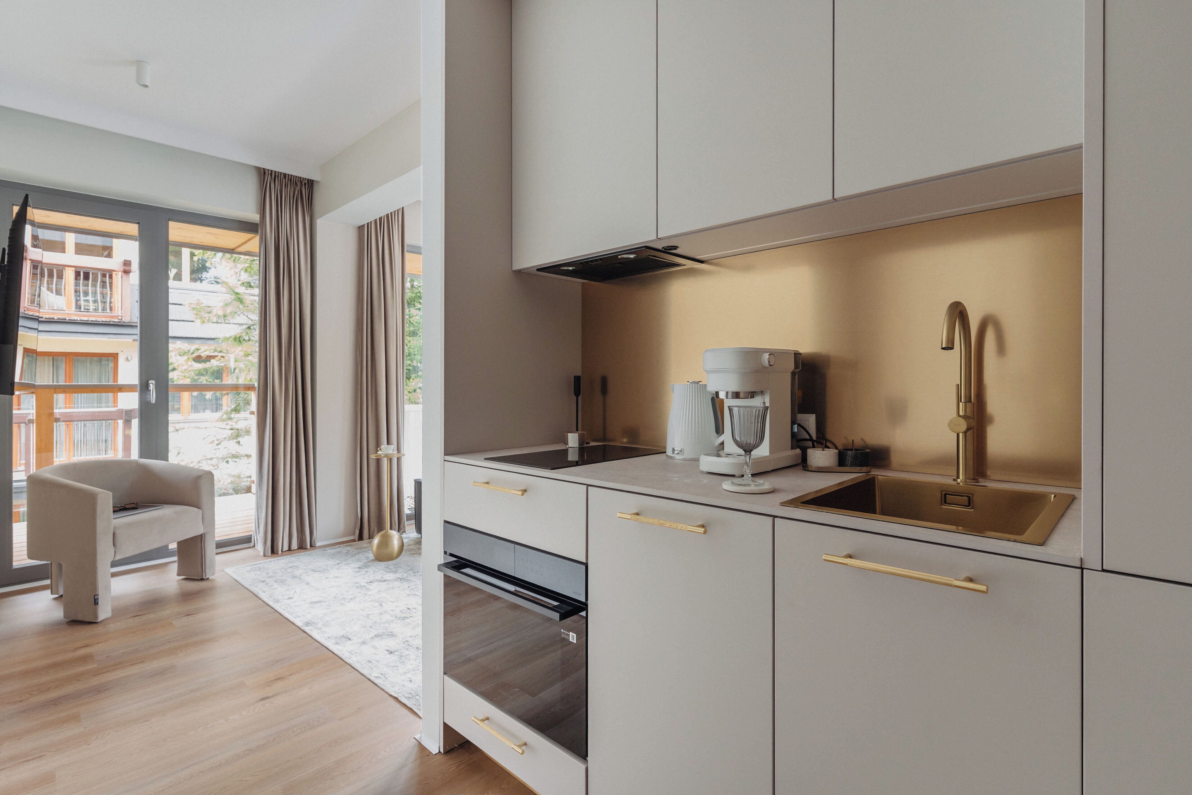 A modern kitchen with a built-in oven, a coffee maker, and a stainless steel sink.