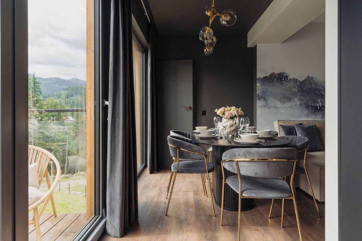 Un comedor moderno con vistas a las montañas, una mesa redonda con sillas y una araña.